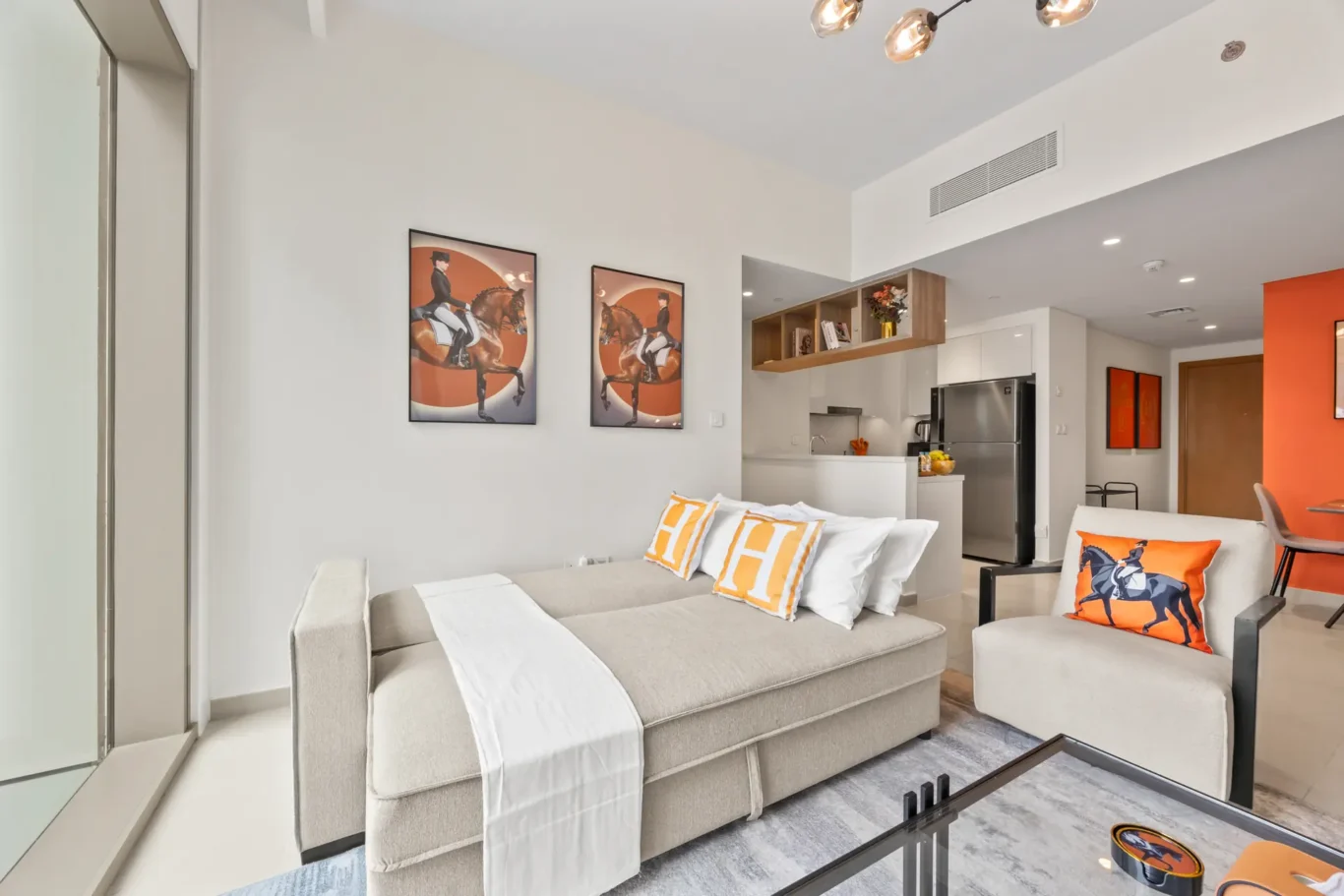 Second bedroom with orange art prints and city view. Day, twilight and night Airbnb photography by MRPS for Vista Haus Holiday Homes in Downtown Dubai.