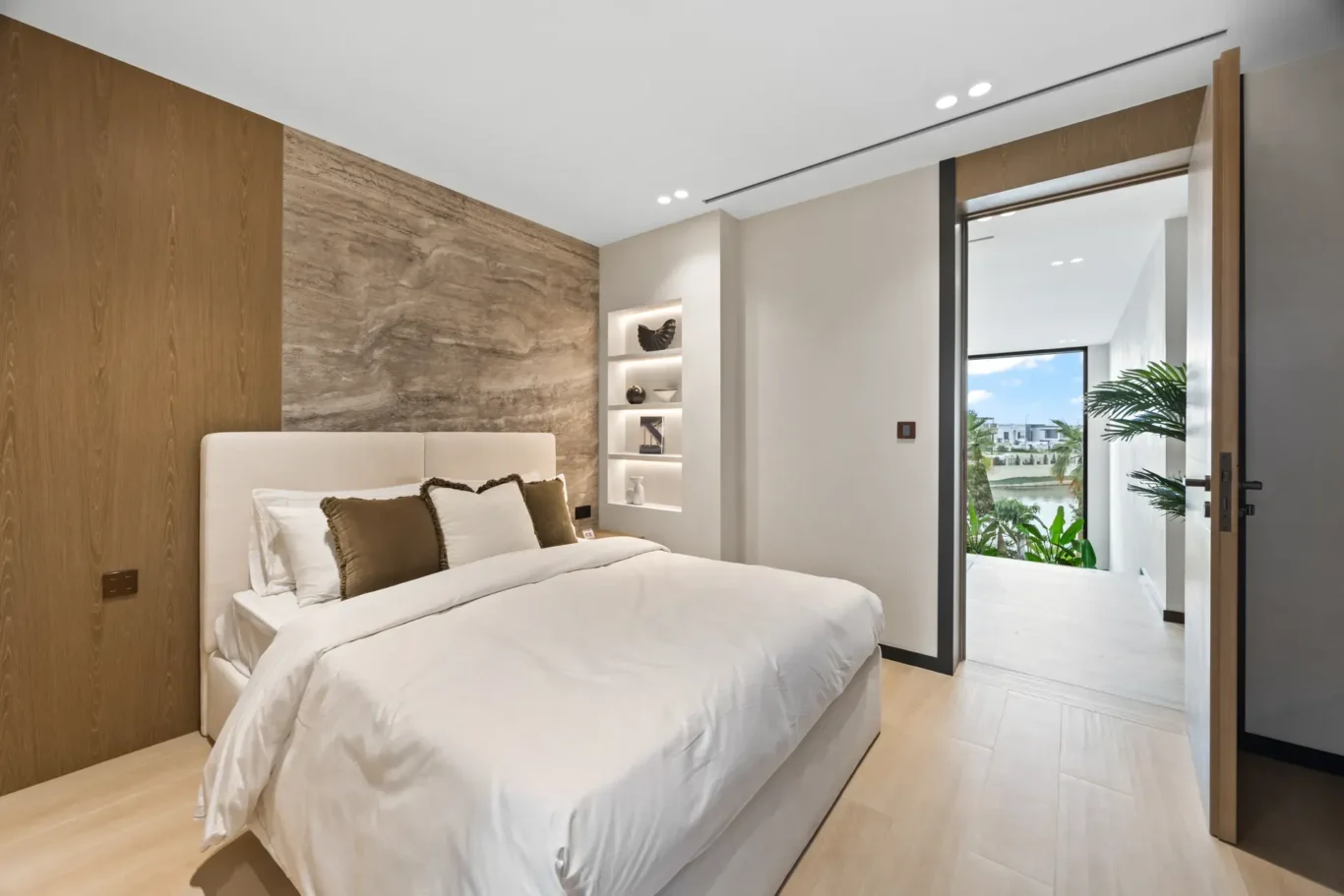 Bedroom with a stone feature wall and a door to the balcony, luxury villa in Jumeirah Islands, Dubai.