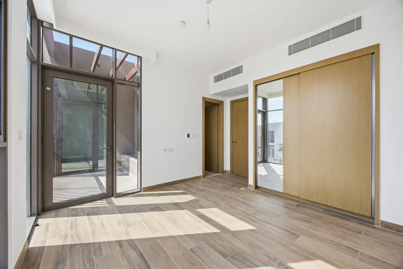 Wide view of the second bedroom with wood flooring. Villa photography by MRPS in Dubai for ELITE Property Brokerage.