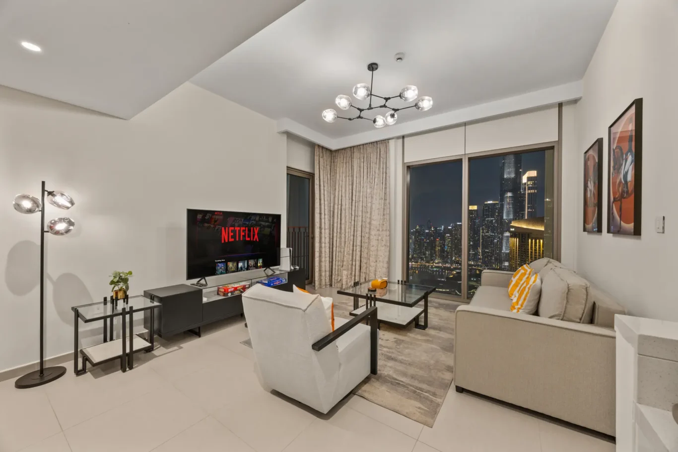 Living room at twilight with the Burj Khalifa lit up through the windows. Day, twilight and night Airbnb photography by MRPS for Vista Haus Holiday Homes in Downtown Dubai.