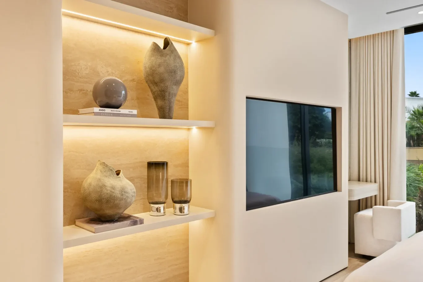 Lit shelves with ceramics beside a wall-mounted TV, luxury villa in Jumeirah Islands, Dubai.
