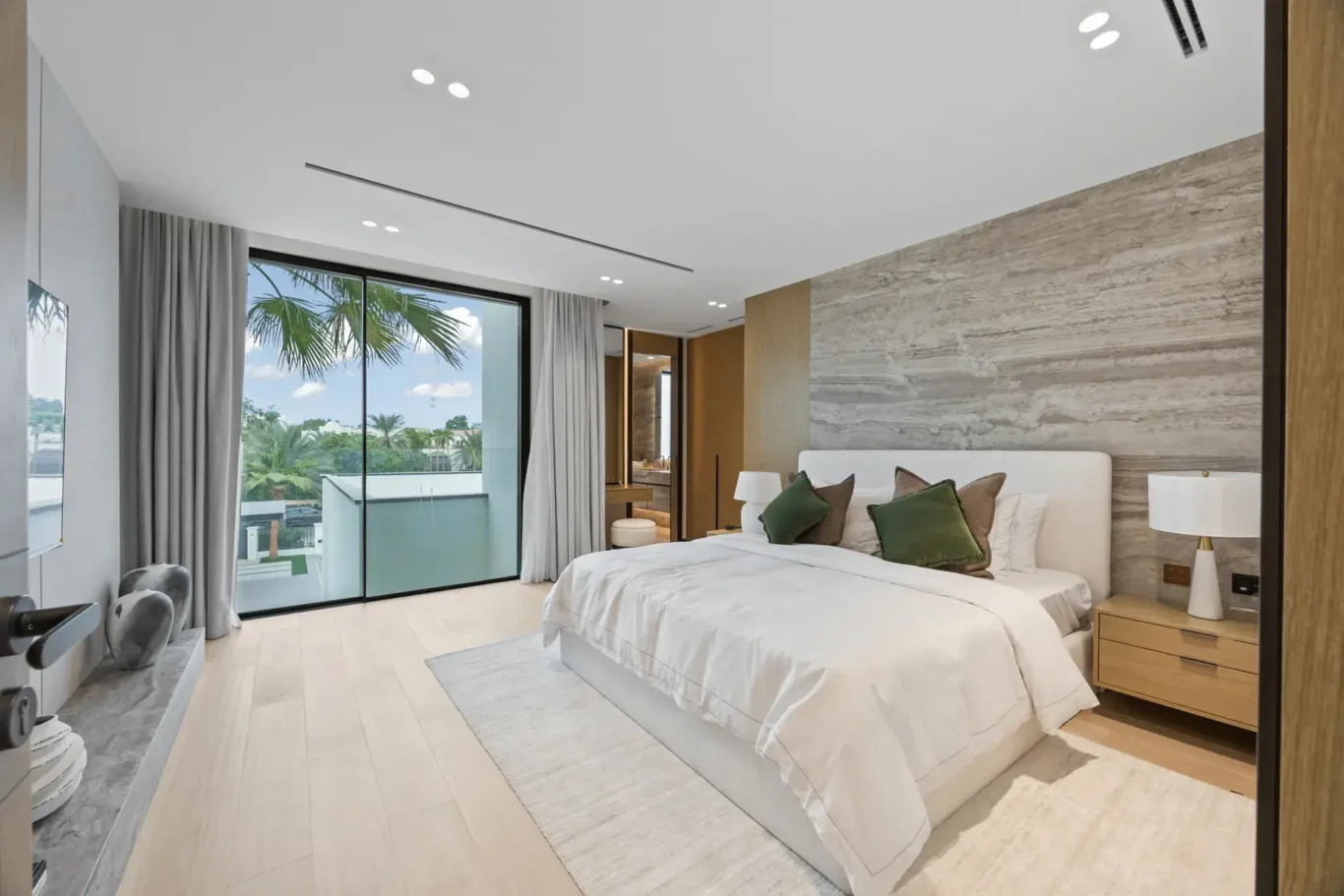 Bedroom with green cushions, a stone wall and a palm view, luxury villa in Jumeirah Islands, Dubai.