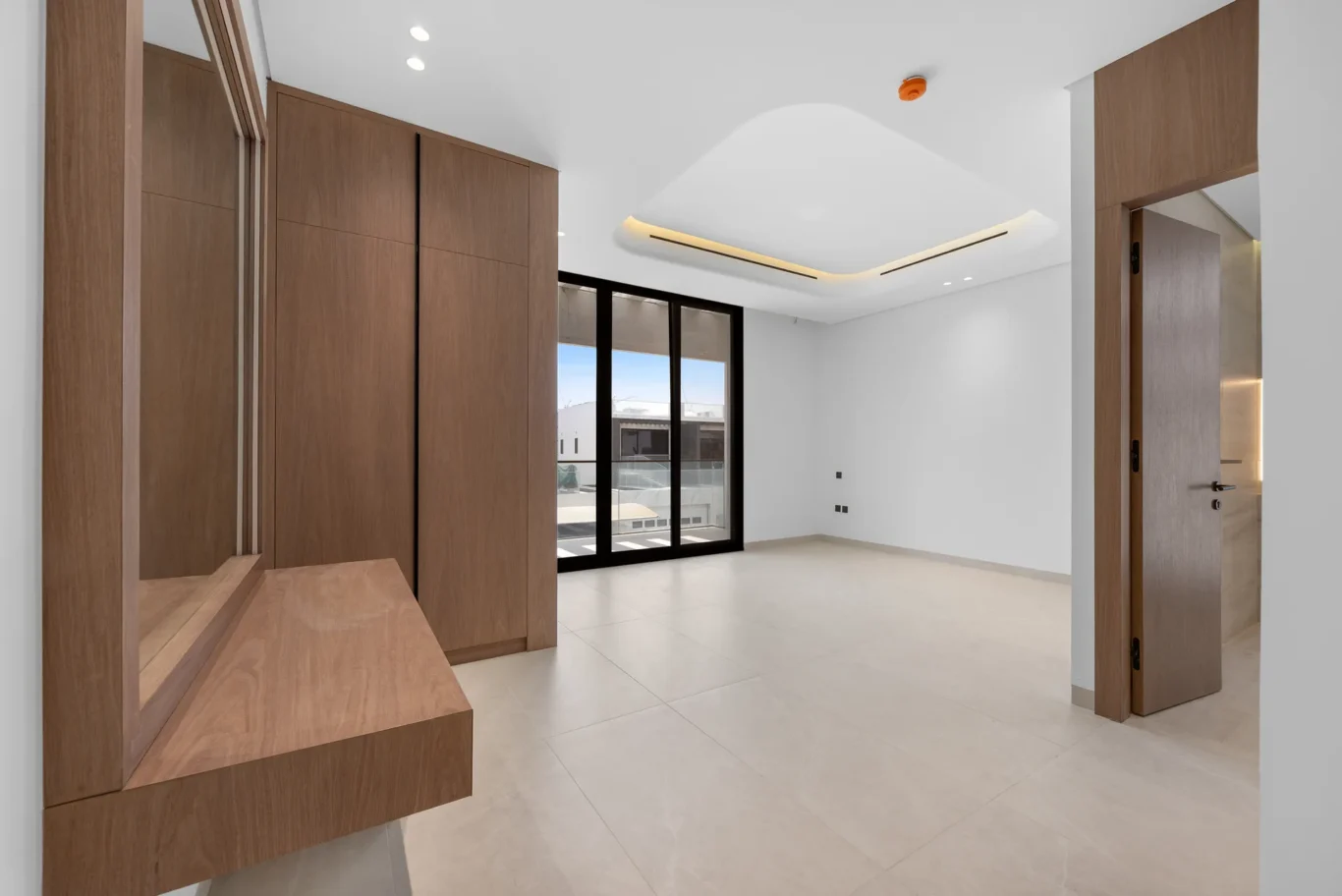 Bedroom with a built-in dressing table and balcony doors, unfurnished five-bedroom villa in Al Furjan, Dubai.