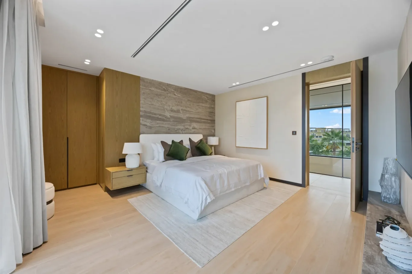 Bedroom with wood wardrobes, artwork and a balcony view, luxury villa in Jumeirah Islands, Dubai.