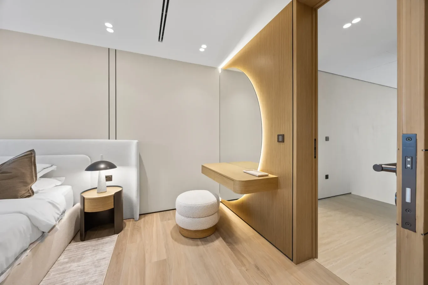 Bedroom with a curved wood feature and dressing table, luxury villa in Jumeirah Islands, Dubai.