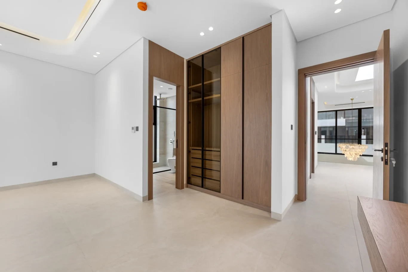 Bedroom with a walk-in wardrobe and walnut joinery, unfurnished five-bedroom villa in Al Furjan, Dubai.