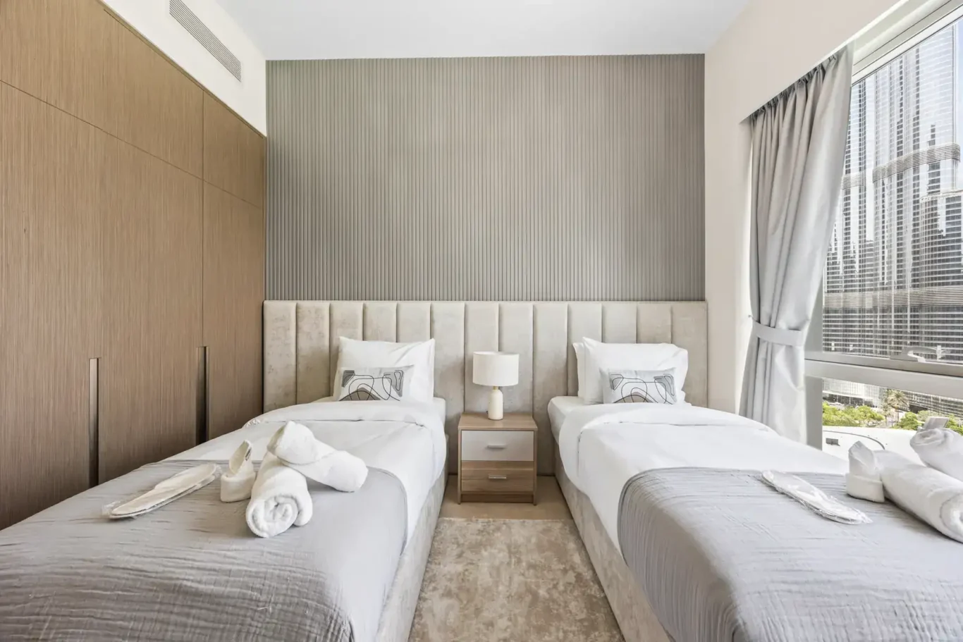 Twin bedroom with window view in a two-bedroom StayComfy Holiday Homes apartment at Grande Signature, Downtown Dubai.
