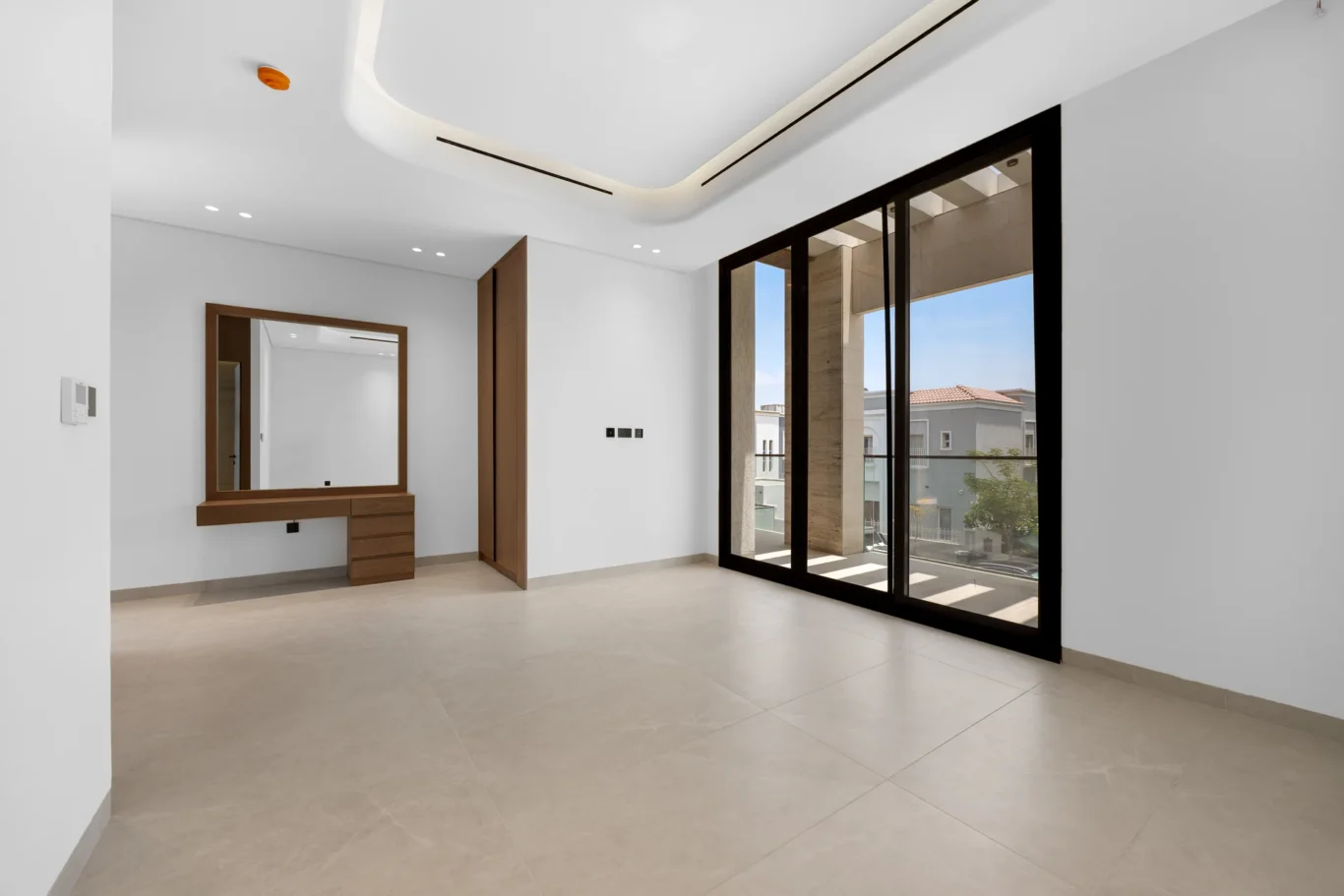 Bedroom with a fitted vanity and sliding doors to the balcony, unfurnished five-bedroom villa in Al Furjan, Dubai.