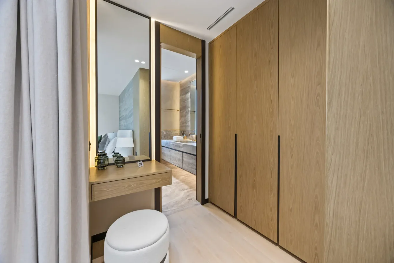 Dressing area with a mirror, wood wardrobes and a stool, luxury villa in Jumeirah Islands, Dubai.