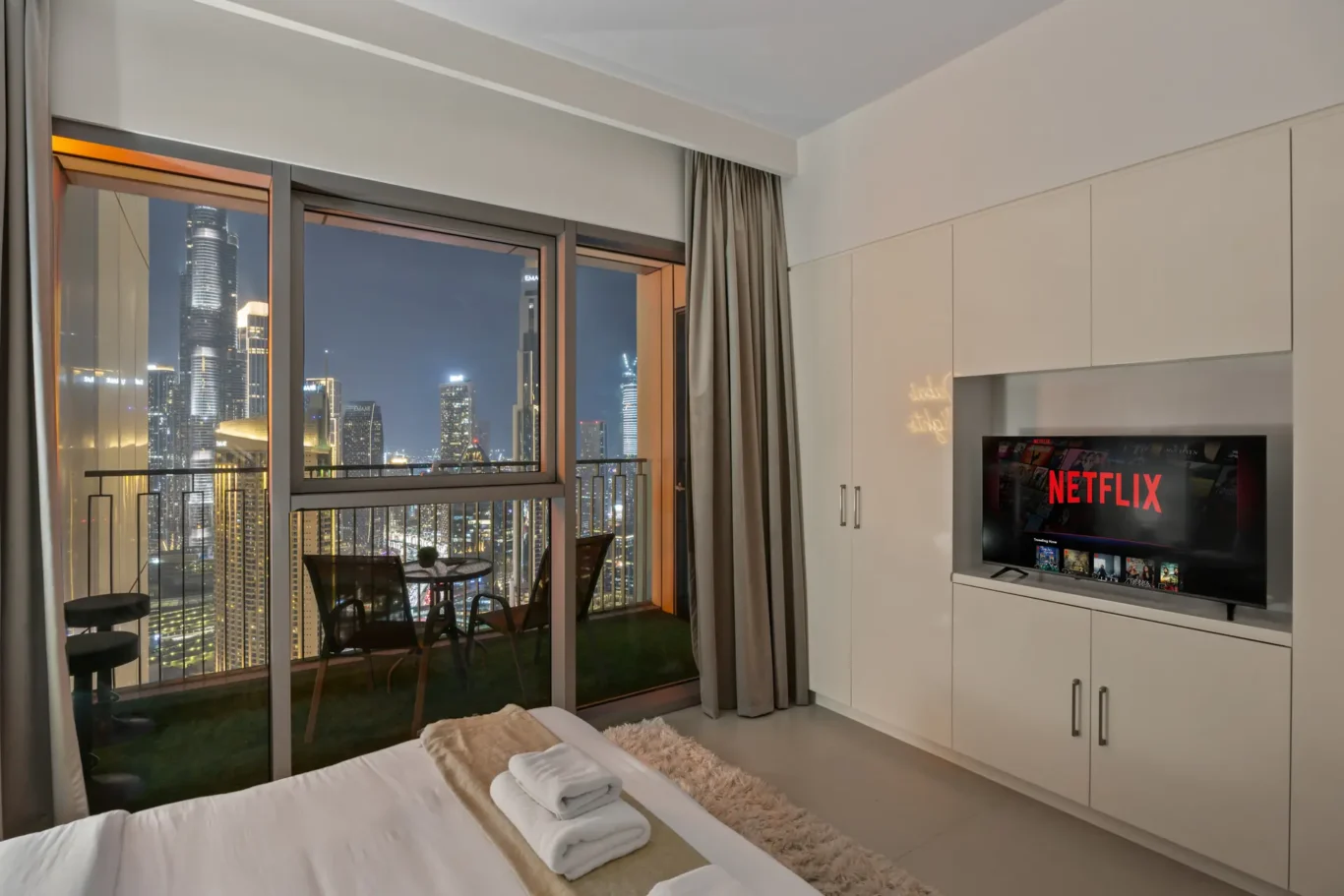 Master bedroom balcony at twilight with artificial grass and city view. Day, twilight and night Airbnb photography by MRPS for Vista Haus Holiday Homes in Downtown Dubai.