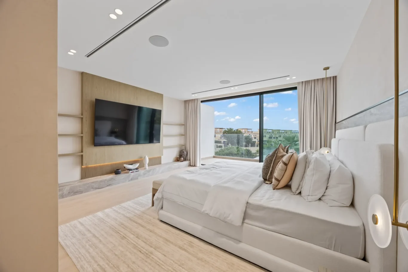 Master bedroom with a TV wall and sliding doors to the terrace, luxury villa in Jumeirah Islands, Dubai.