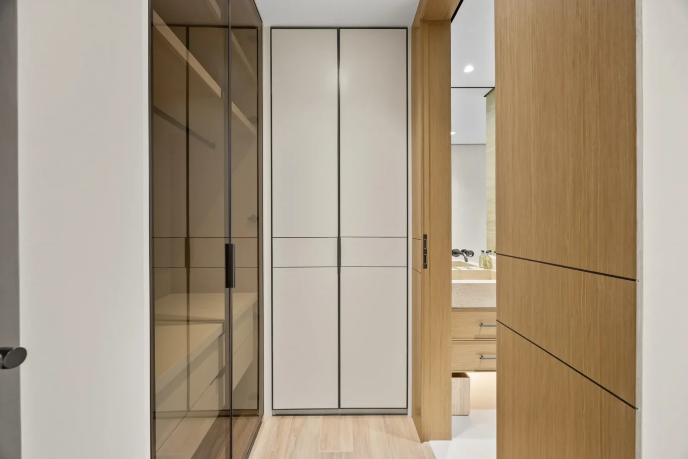Walk-in wardrobe with glass and wood doors, luxury villa in Jumeirah Islands, Dubai.