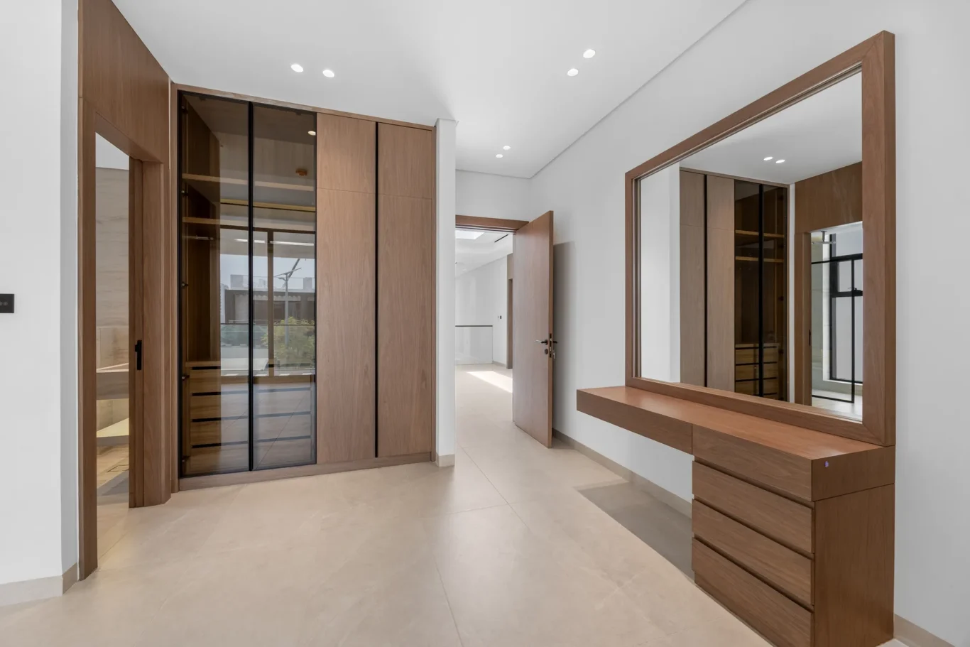 Bedroom dressing area with a mirror and glass-front wardrobe, unfurnished five-bedroom villa in Al Furjan, Dubai.