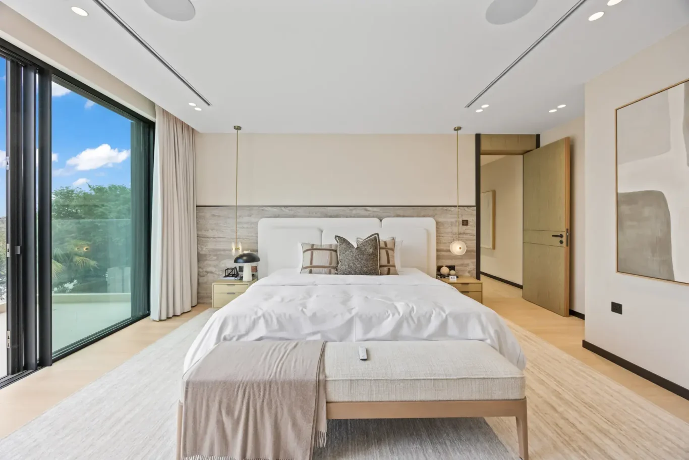 Master bedroom bed with a bench and floor-to-ceiling windows, luxury villa in Jumeirah Islands, Dubai.