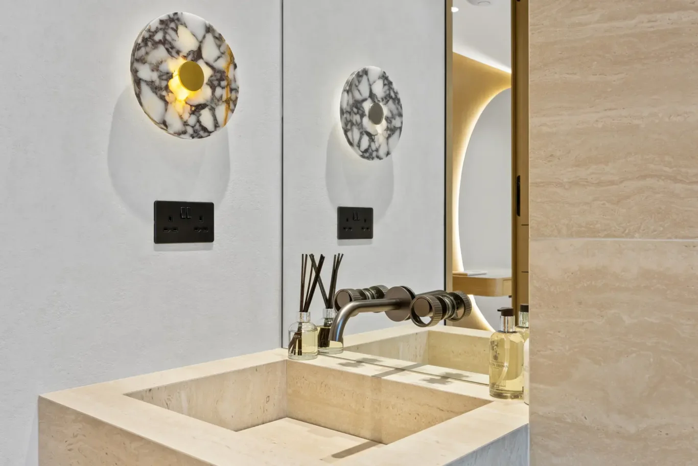 Stone basin with a wall tap and round stone mirrors, luxury villa in Jumeirah Islands, Dubai.