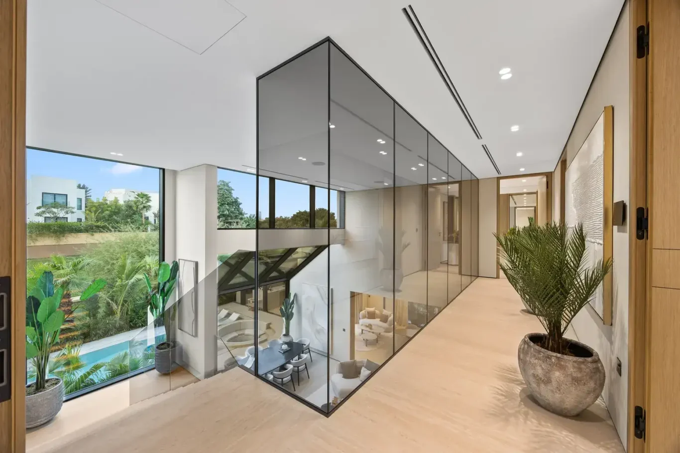 Upper landing with a glass void overlooking the living room and pool, luxury villa in Jumeirah Islands, Dubai.