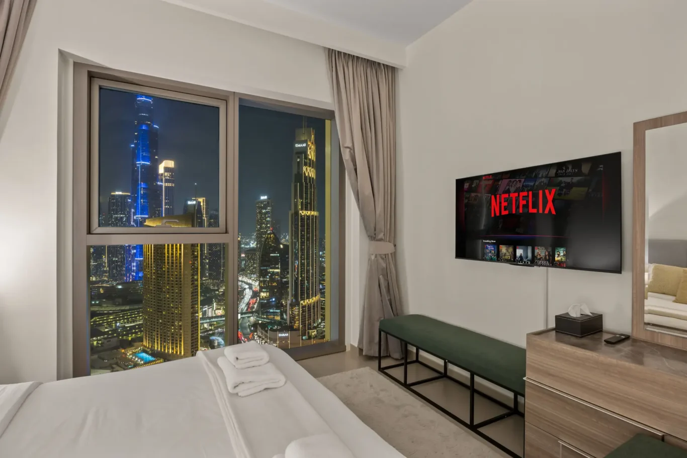 Second bedroom at twilight with the city skyline in the window. Day, twilight and night Airbnb photography by MRPS for Vista Haus Holiday Homes in Downtown Dubai.