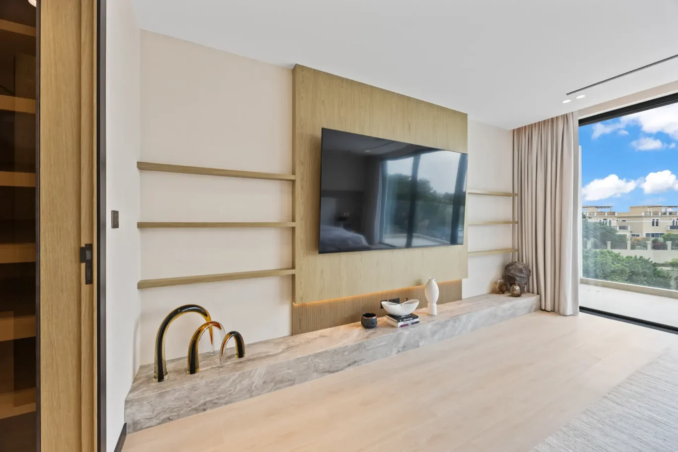 Master bedroom media wall with shelves and a balcony view, luxury villa in Jumeirah Islands, Dubai.