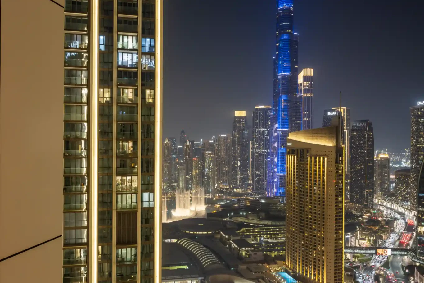 Master bedroom at night with the TV wall and the Burj Khalifa lights outside. Day, twilight and night Airbnb photography by MRPS for Vista Haus Holiday Homes in Downtown Dubai.