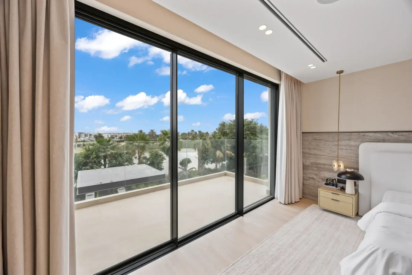 Master bedroom sliding doors opening onto the terrace under a blue sky, luxury villa in Jumeirah Islands, Dubai.