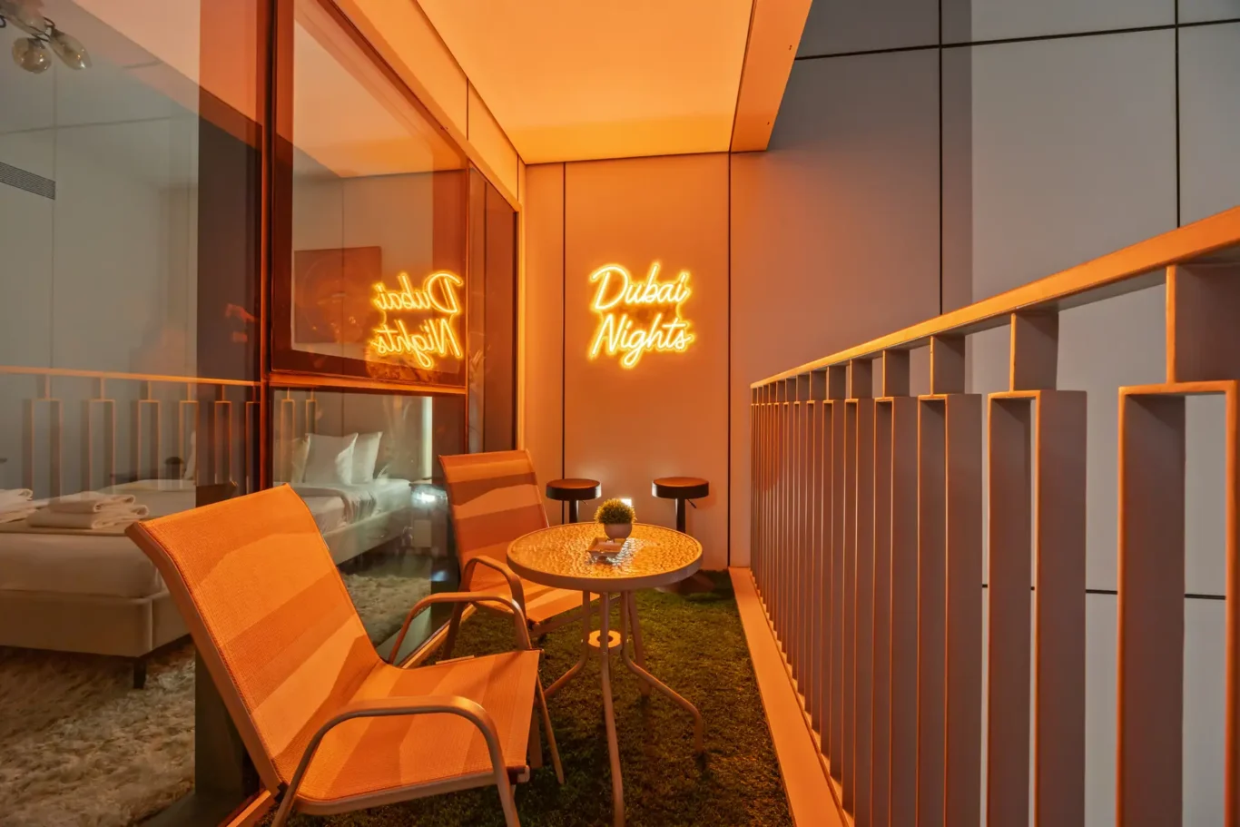 Balcony at night with the Dubai Nights neon sign and the Burj Khalifa. Day, twilight and night Airbnb photography by MRPS for Vista Haus Holiday Homes in Downtown Dubai.