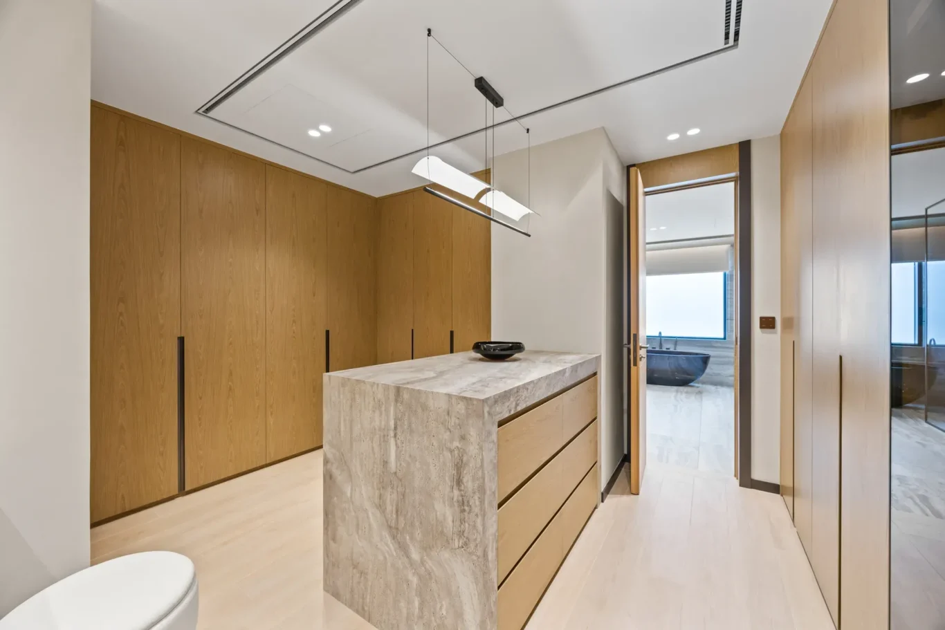 Walk-in dressing room with a stone island and wood wardrobes, luxury villa in Jumeirah Islands, Dubai.