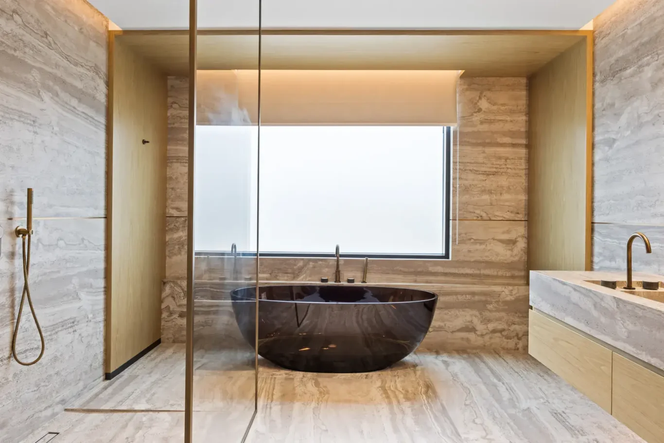 Master bathroom with a freestanding black stone bathtub and travertine walls, luxury villa in Jumeirah Islands, Dubai.