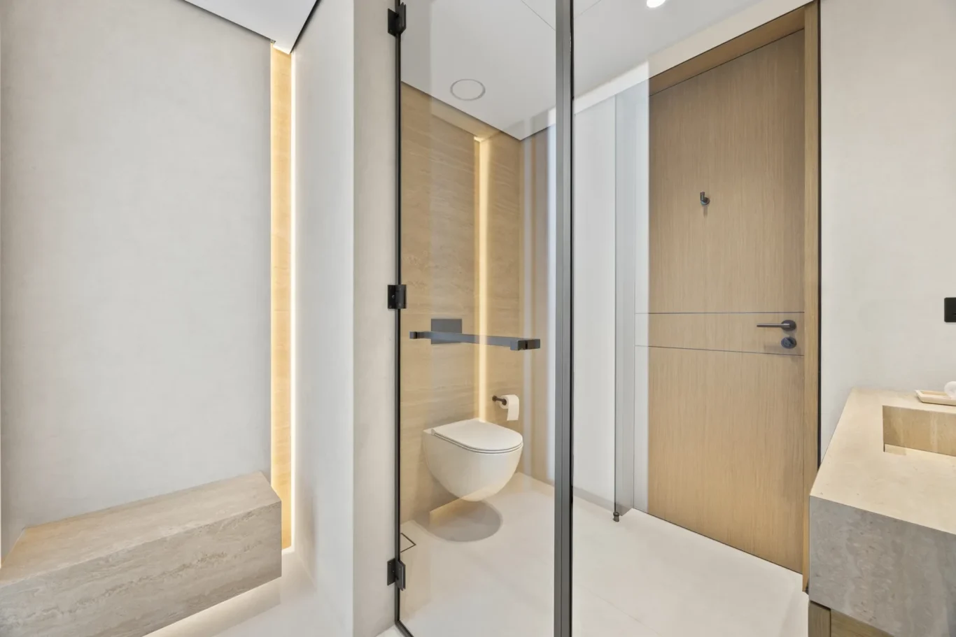 Bathroom with a lit wall niche and wood door, luxury villa in Jumeirah Islands, Dubai.