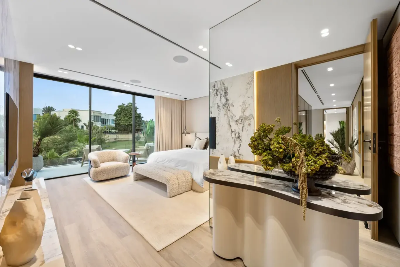 Master bedroom with a marble console and floor-to-ceiling garden view, luxury villa in Jumeirah Islands, Dubai.