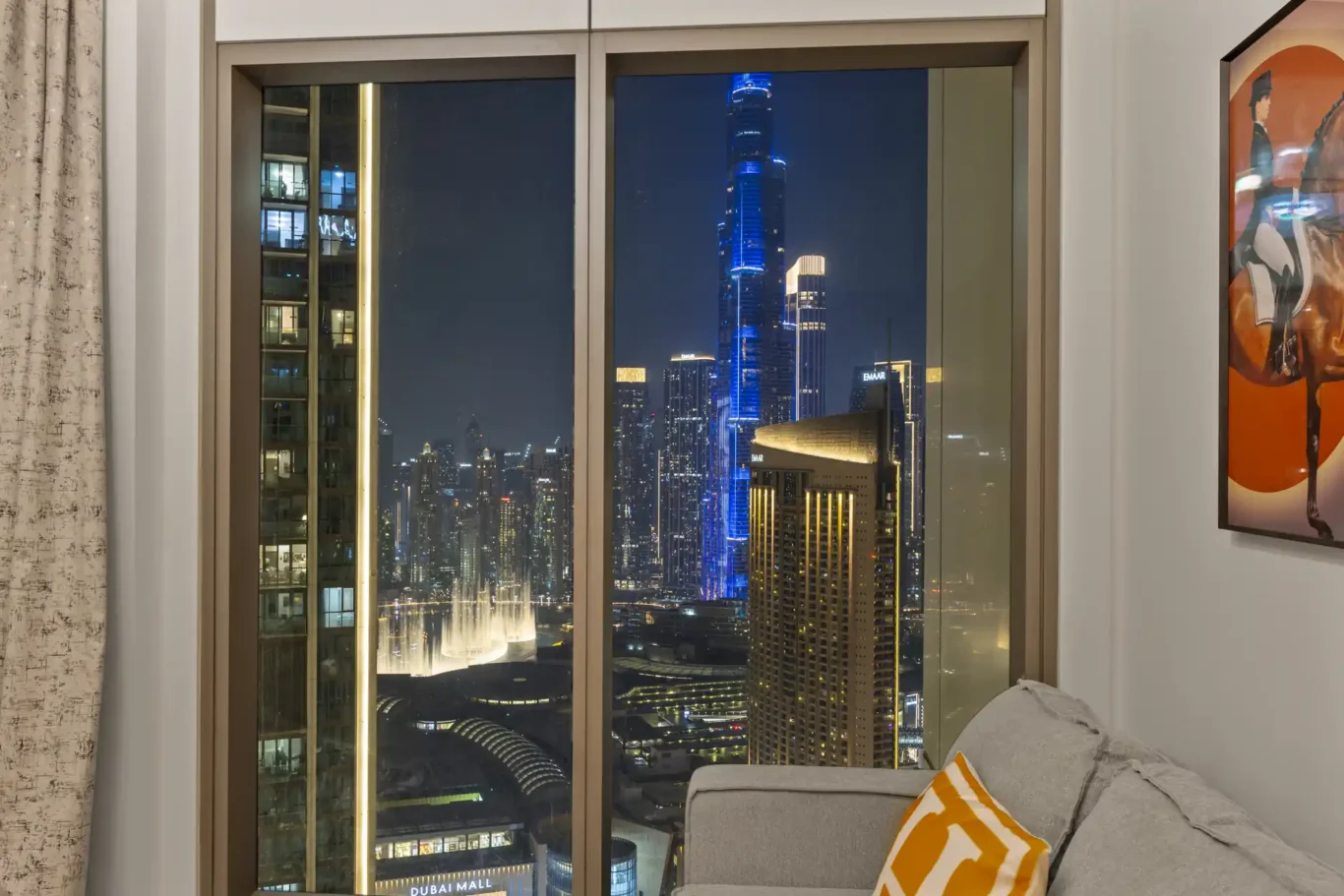 Burj Khalifa with blue lights at night from the apartment window. Day, twilight and night Airbnb photography by MRPS for Vista Haus Holiday Homes in Downtown Dubai.