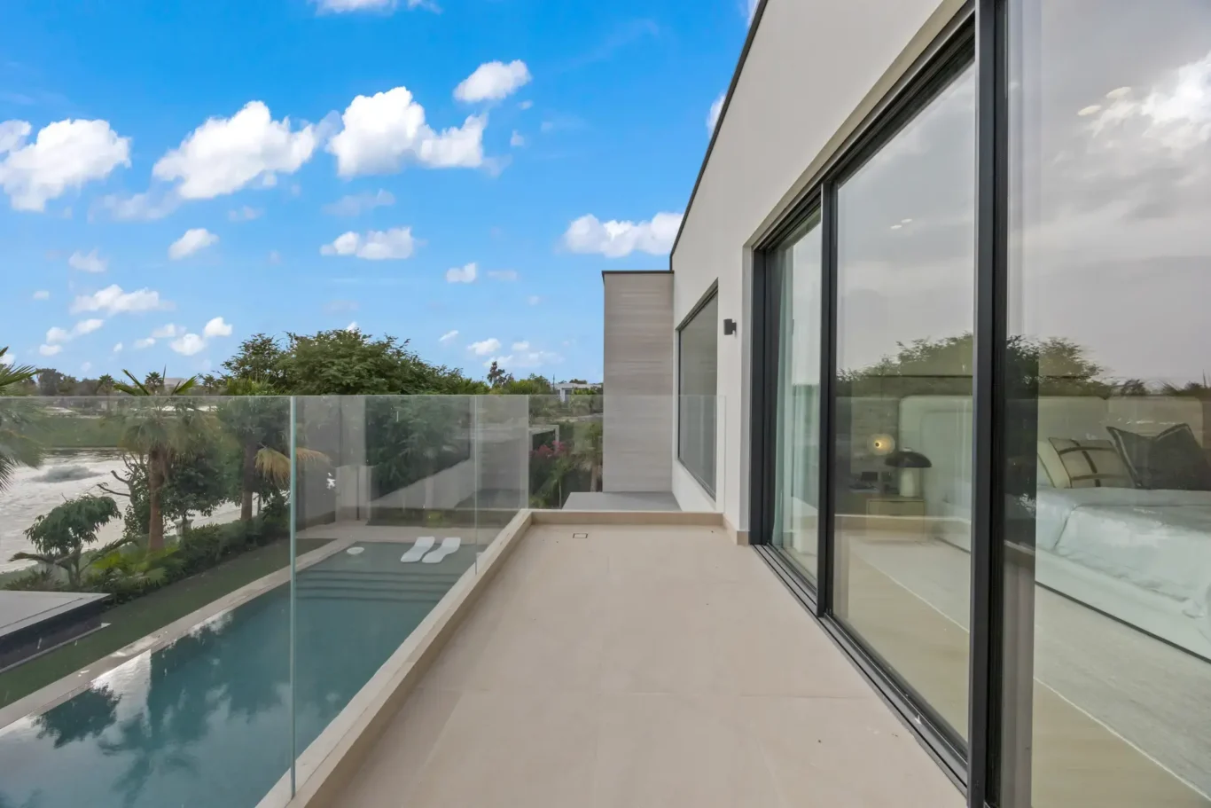 Upper terrace with a glass balustrade overlooking the pool, luxury villa in Jumeirah Islands, Dubai.