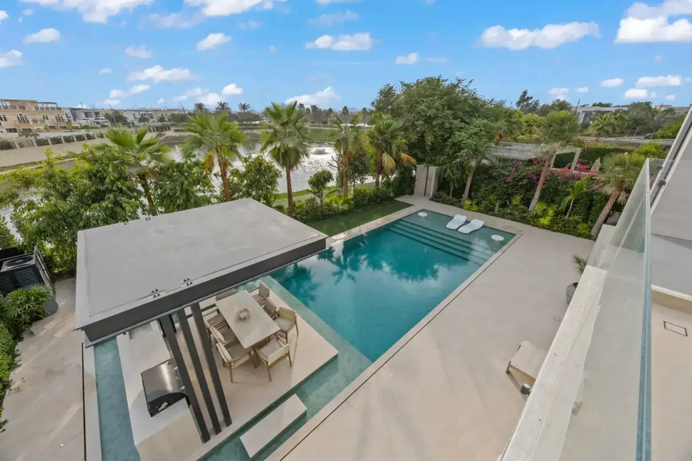 View from the terrace down to the swimming pool, dining pergola and garden, luxury villa in Jumeirah Islands, Dubai.