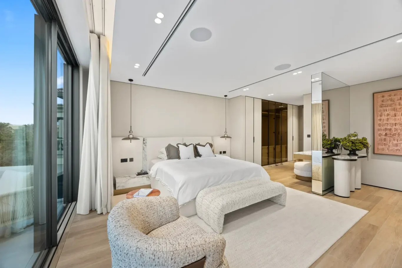 Master bedroom bed and bench beside floor-to-ceiling windows, luxury villa in Jumeirah Islands, Dubai.
