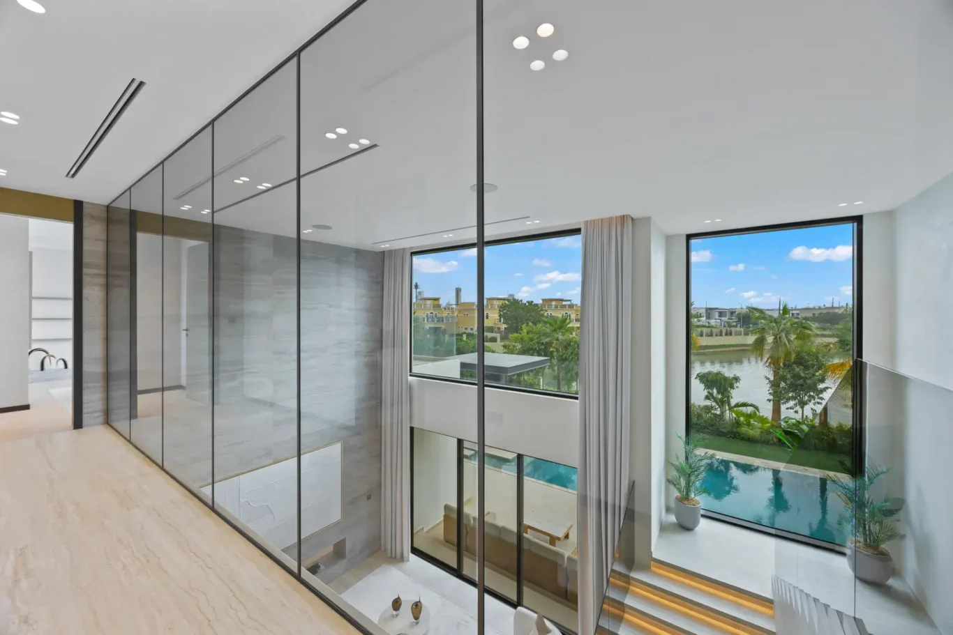 Glass landing overlooking the double-height living room and pool, luxury villa in Jumeirah Islands, Dubai.