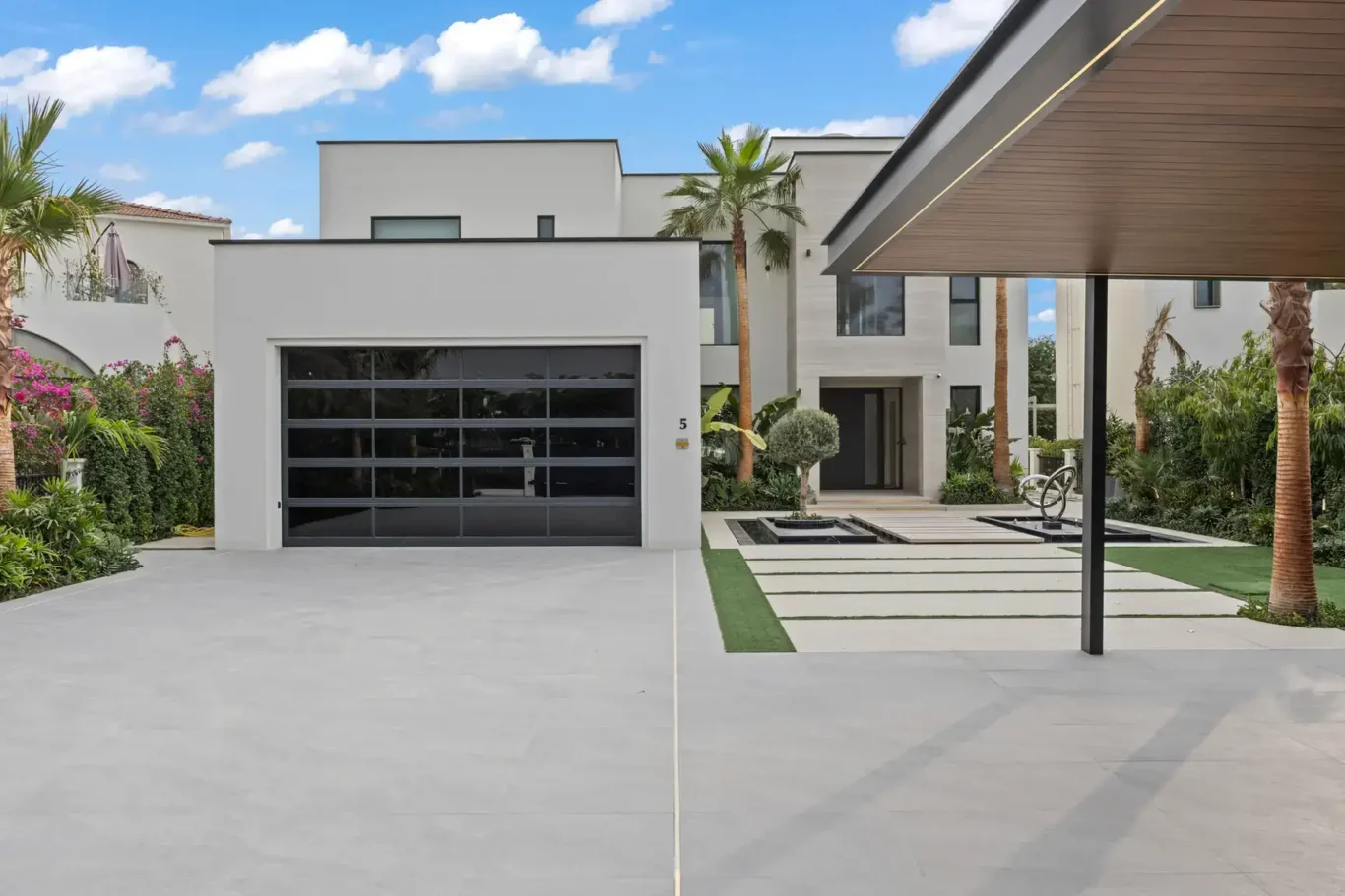 Front exterior with the garage, carport and palm trees, luxury villa in Jumeirah Islands, Dubai.