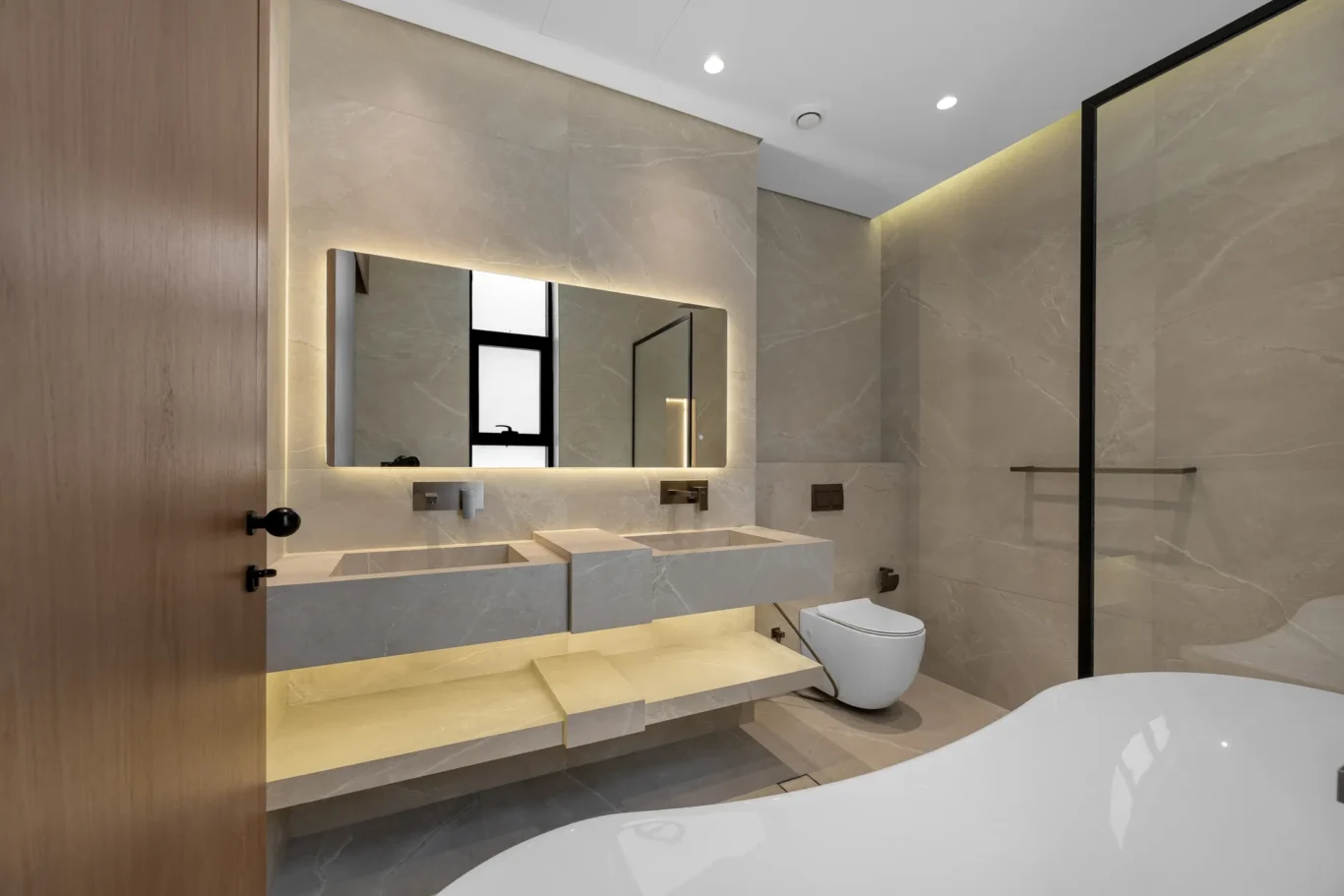 Bathroom with a double vanity, backlit mirror and bathtub, unfurnished five-bedroom villa in Al Furjan, Dubai.