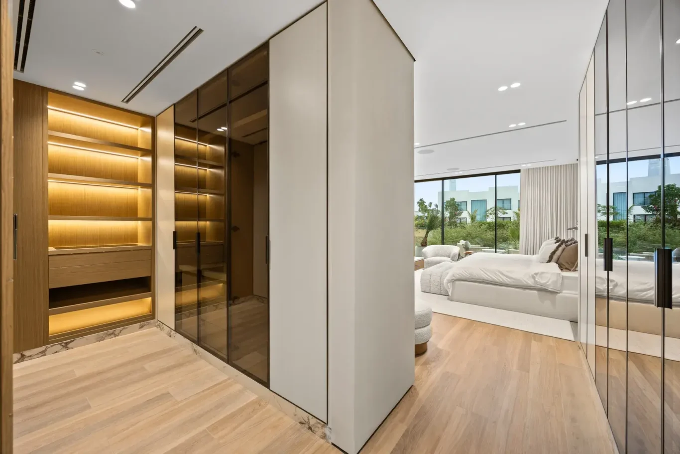 Master walk-in wardrobe with lit shelves and glass doors, luxury villa in Jumeirah Islands, Dubai.