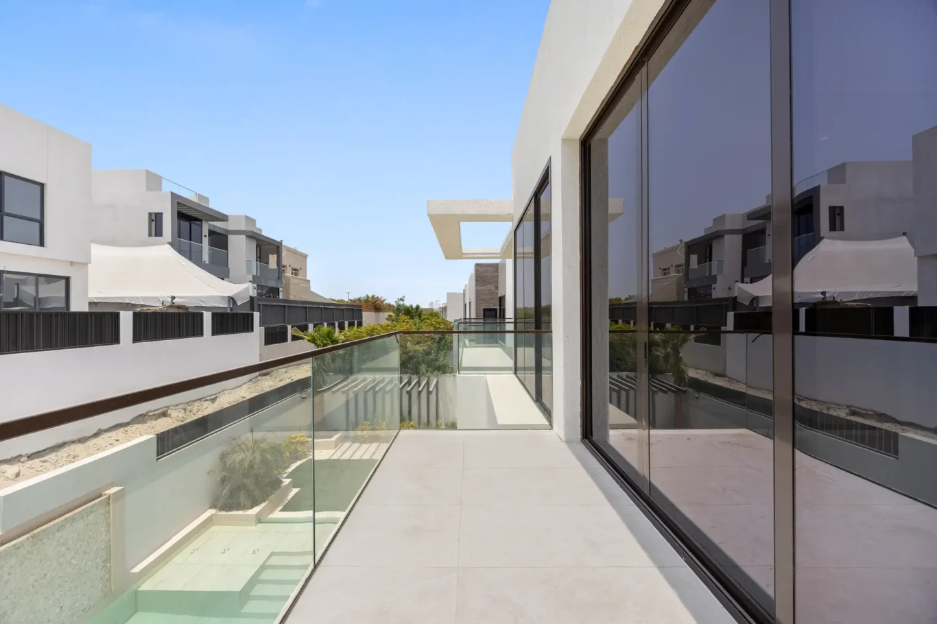 Terrace with a glass balustrade overlooking the pool, unfurnished five-bedroom villa in Al Furjan, Dubai.