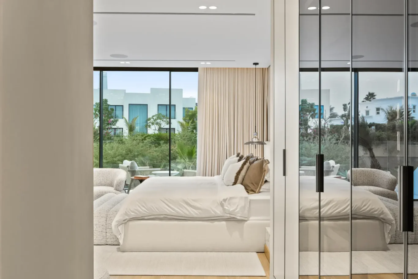 Master bedroom seen through the glass wardrobe partition, luxury villa in Jumeirah Islands, Dubai.