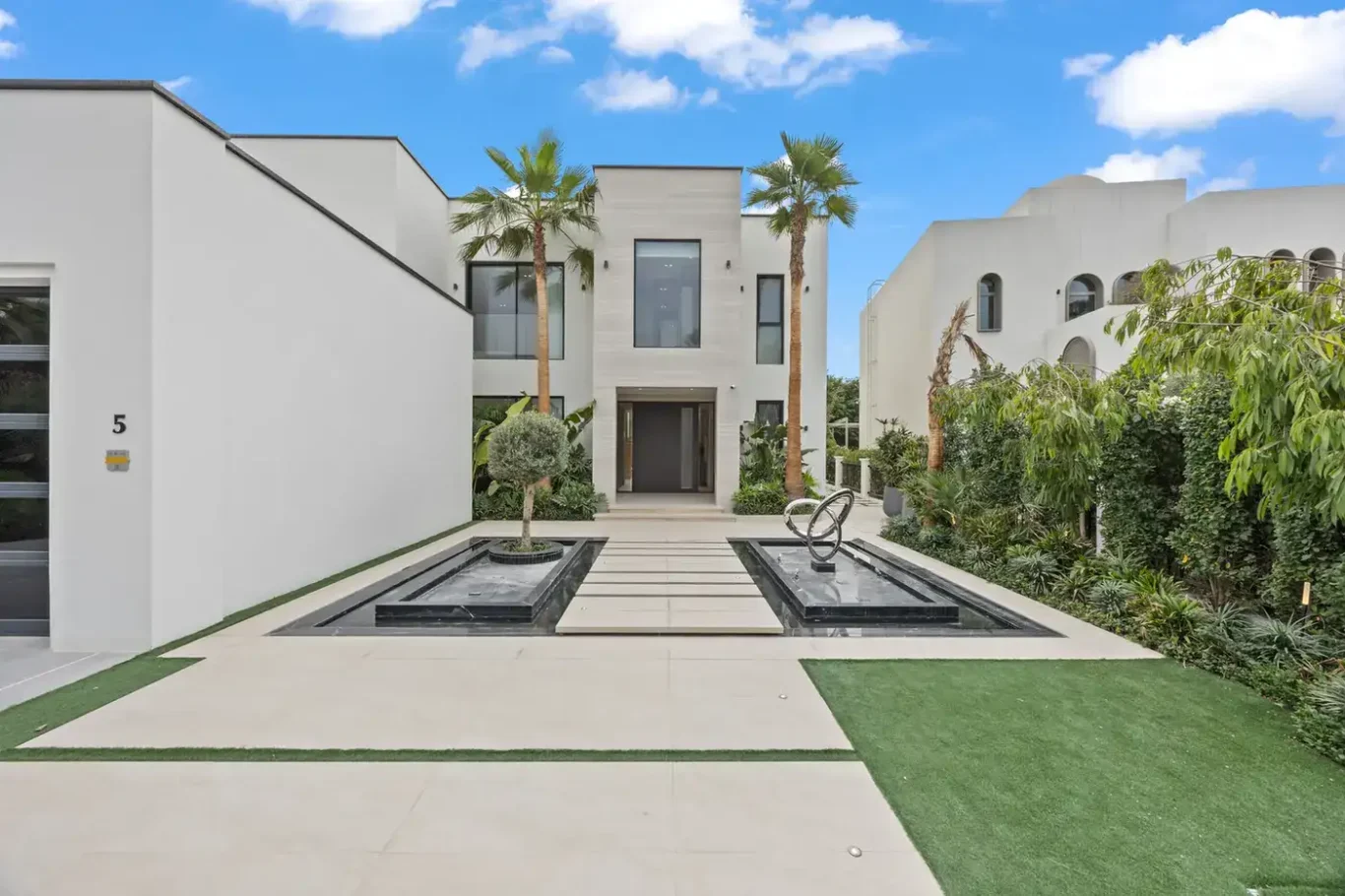Front entrance path with water features and palm trees, luxury villa in Jumeirah Islands, Dubai.