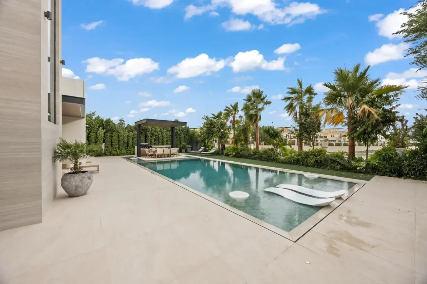 Pool deck with in-water loungers and a garden of palm trees, luxury villa in Jumeirah Islands, Dubai.