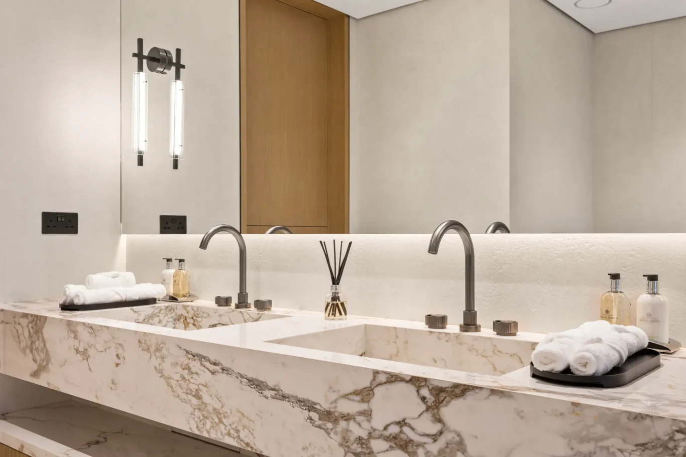 Marble double basin with brushed taps and rolled towels, luxury villa in Jumeirah Islands, Dubai.