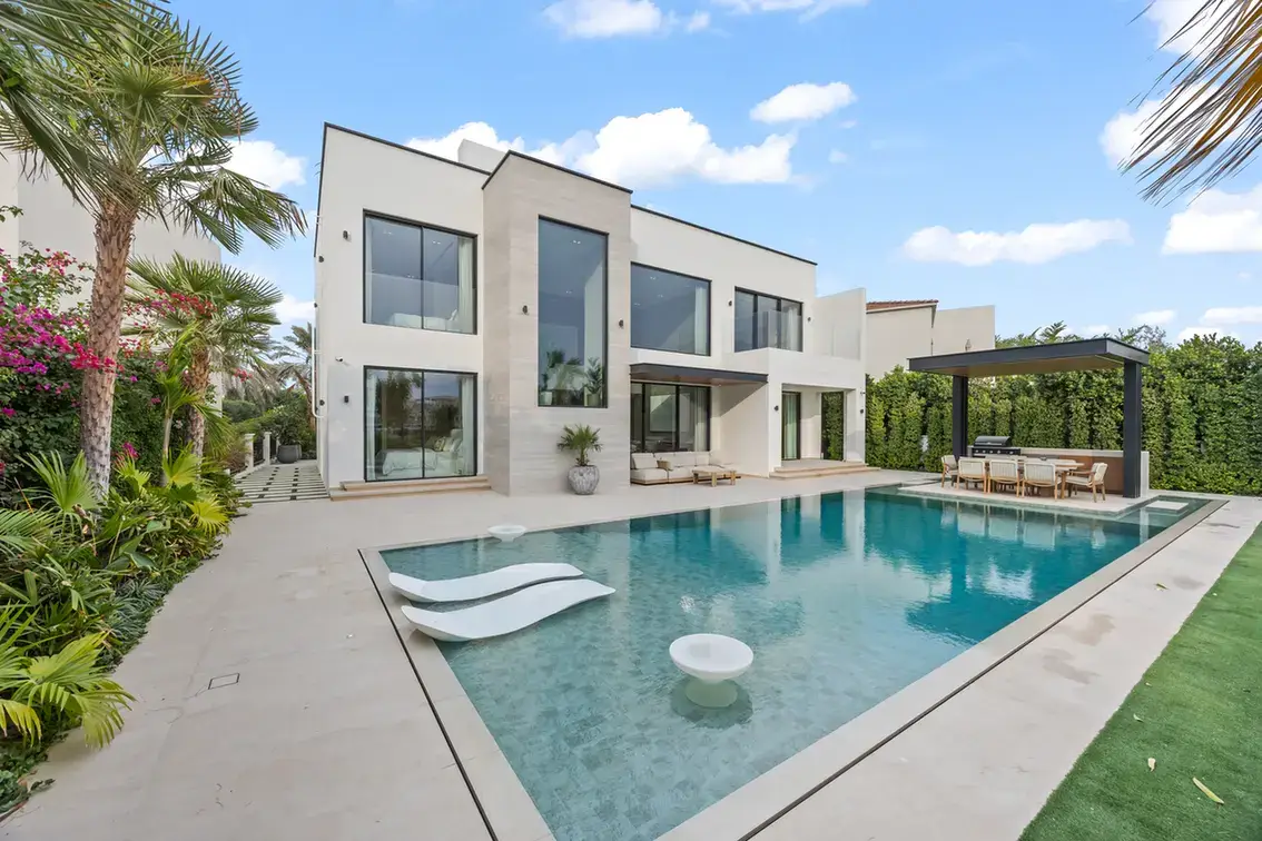 Rear facade of the villa with the swimming pool and in-water loungers, luxury villa in Jumeirah Islands, Dubai.