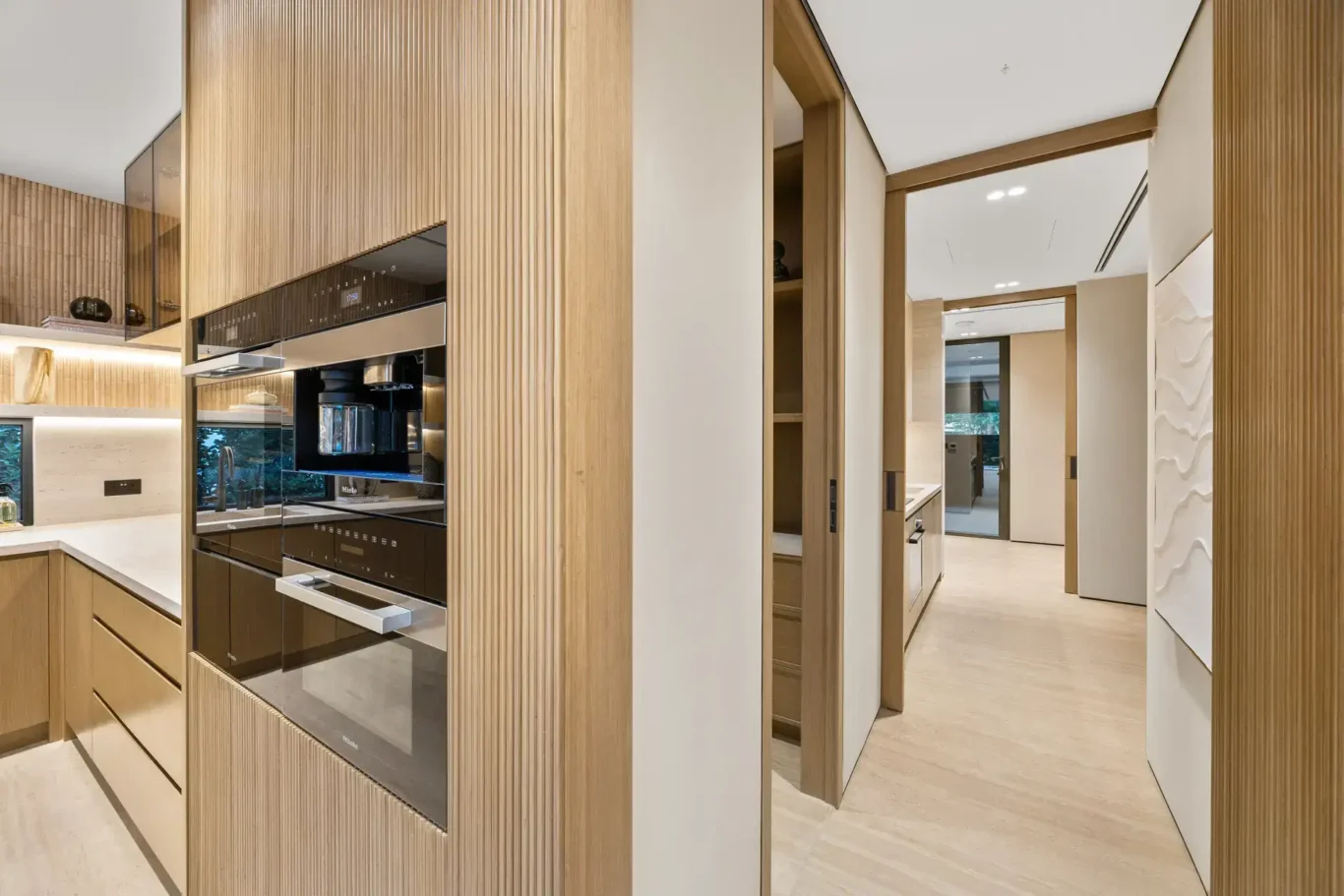 Back kitchen with built-in ovens and wood cabinetry, luxury villa in Jumeirah Islands, Dubai.