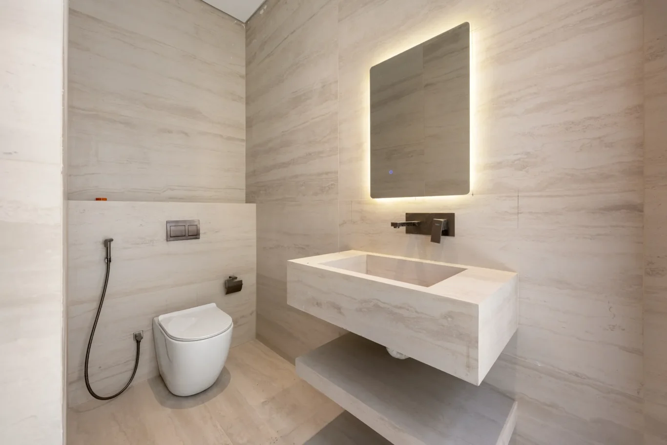 Powder room with a stone basin and backlit mirror, unfurnished five-bedroom villa in Al Furjan, Dubai.