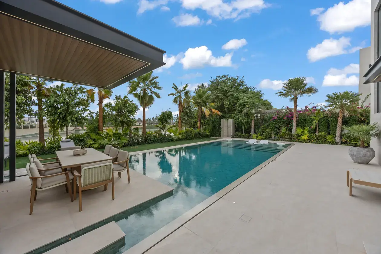 Poolside dining table under the pergola with garden views, luxury villa in Jumeirah Islands, Dubai.