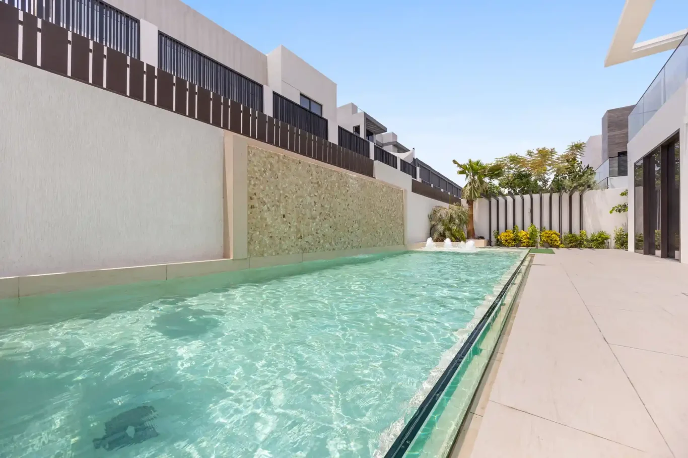 Swimming pool with a mosaic water wall, unfurnished five-bedroom villa in Al Furjan, Dubai.