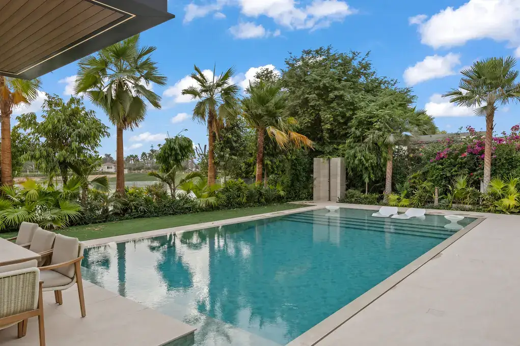 Swimming pool surrounded by palm trees and landscaped garden, luxury villa in Jumeirah Islands, Dubai.