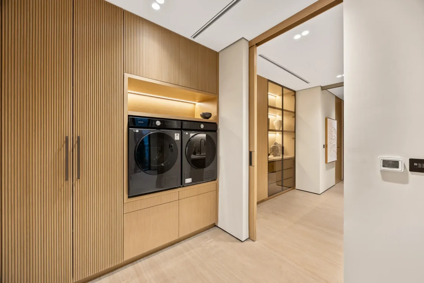 Laundry area with a washer and dryer in fluted wood cabinetry, luxury villa in Jumeirah Islands, Dubai.