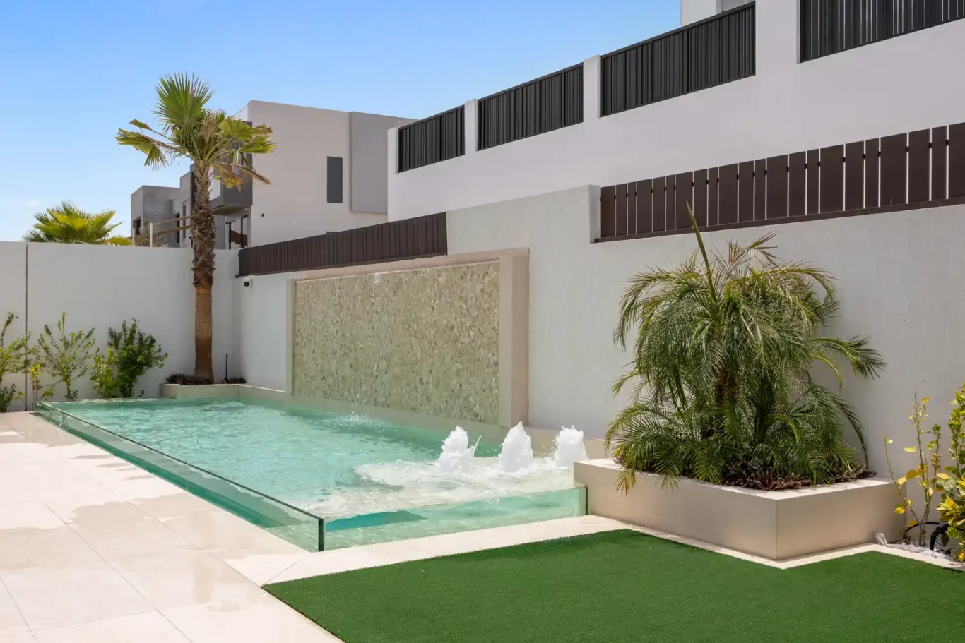 Swimming pool with fountains beside a garden planter, unfurnished five-bedroom villa in Al Furjan, Dubai.